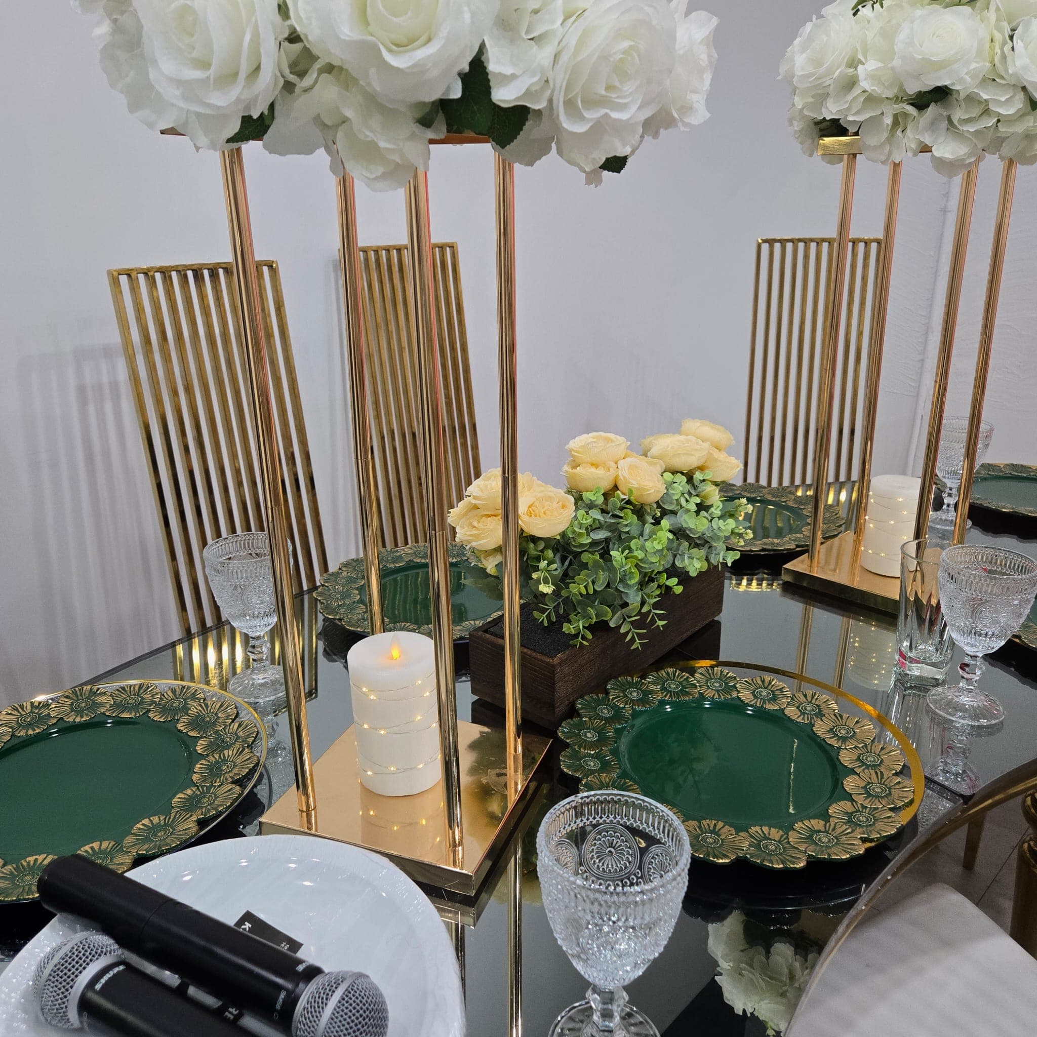 Emerald green and gold place settings with candles and microphones.