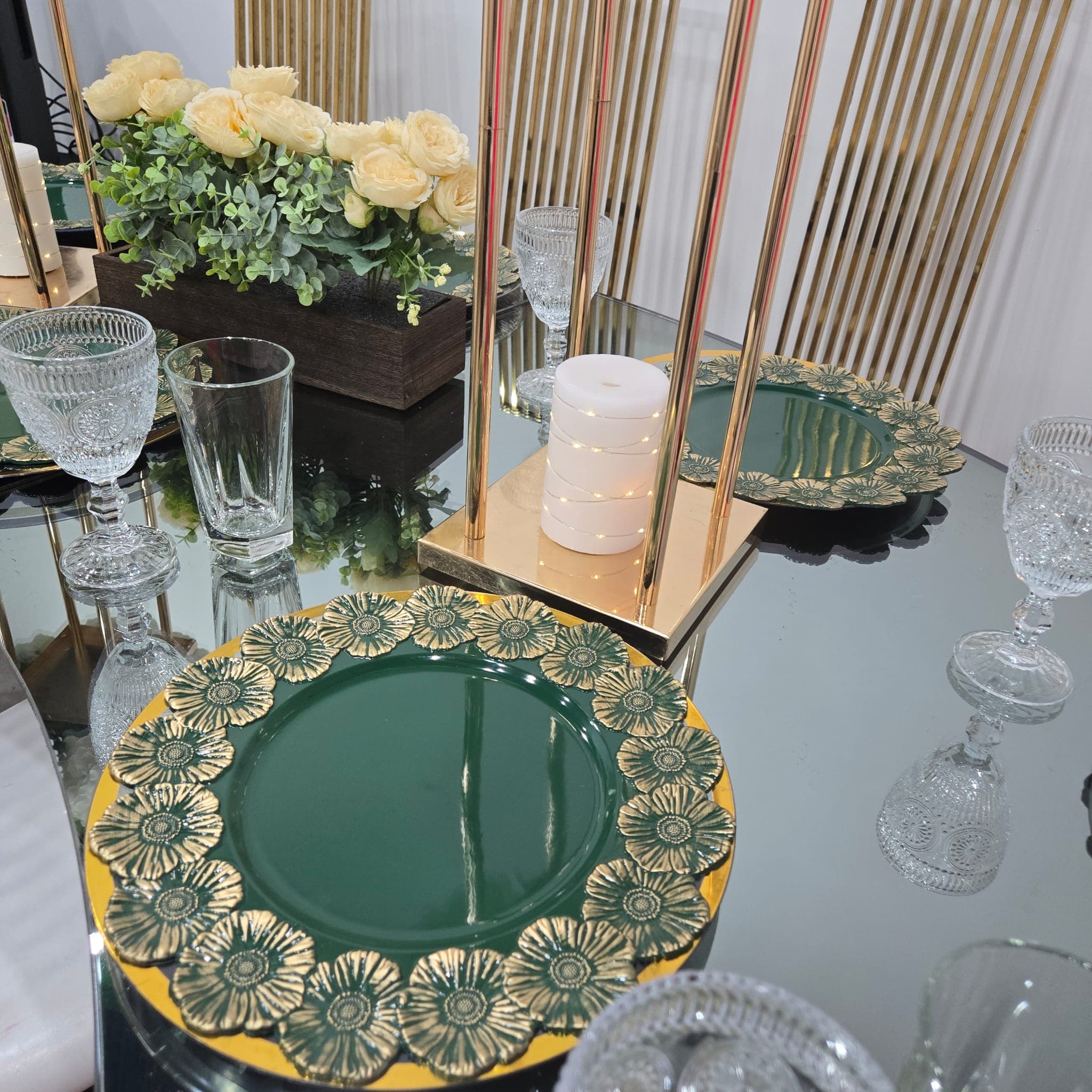 Green charger plates with gold floral detail on a mirrored table.