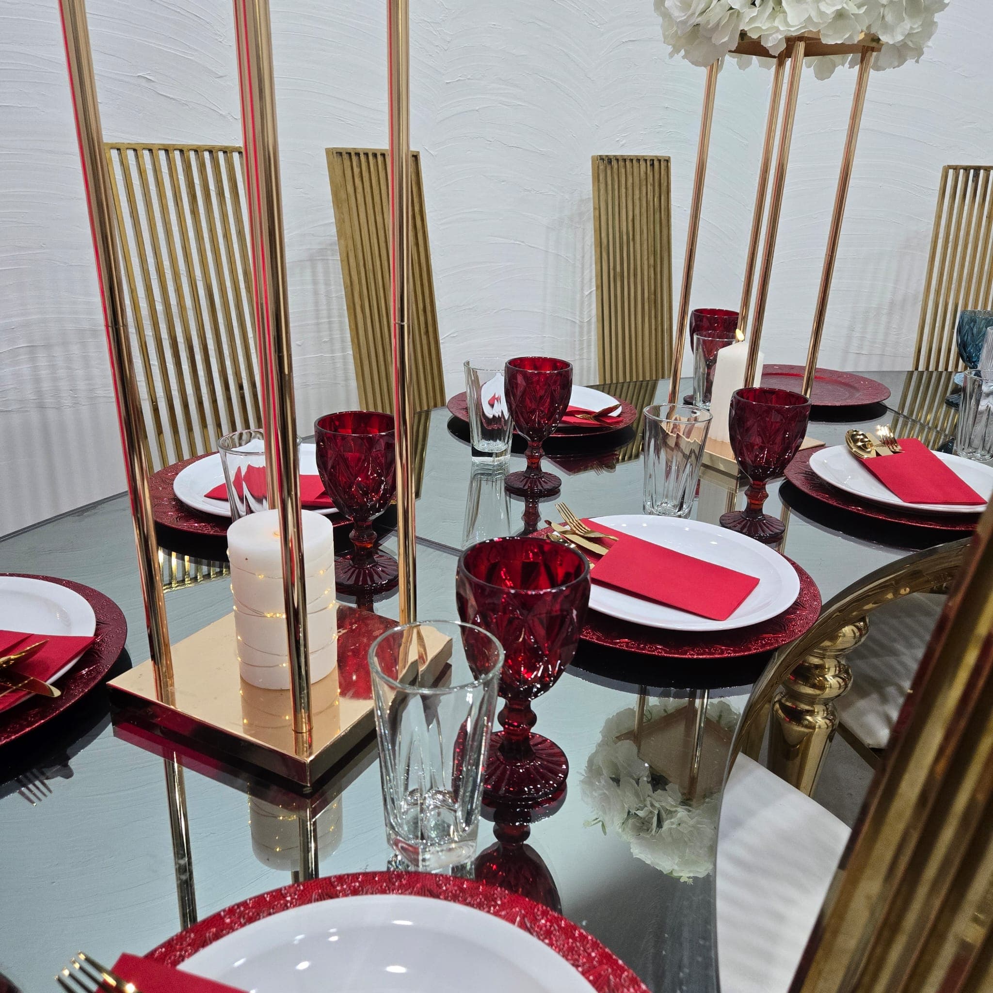 Red and gold table styling with crystal glassware and white roses.
