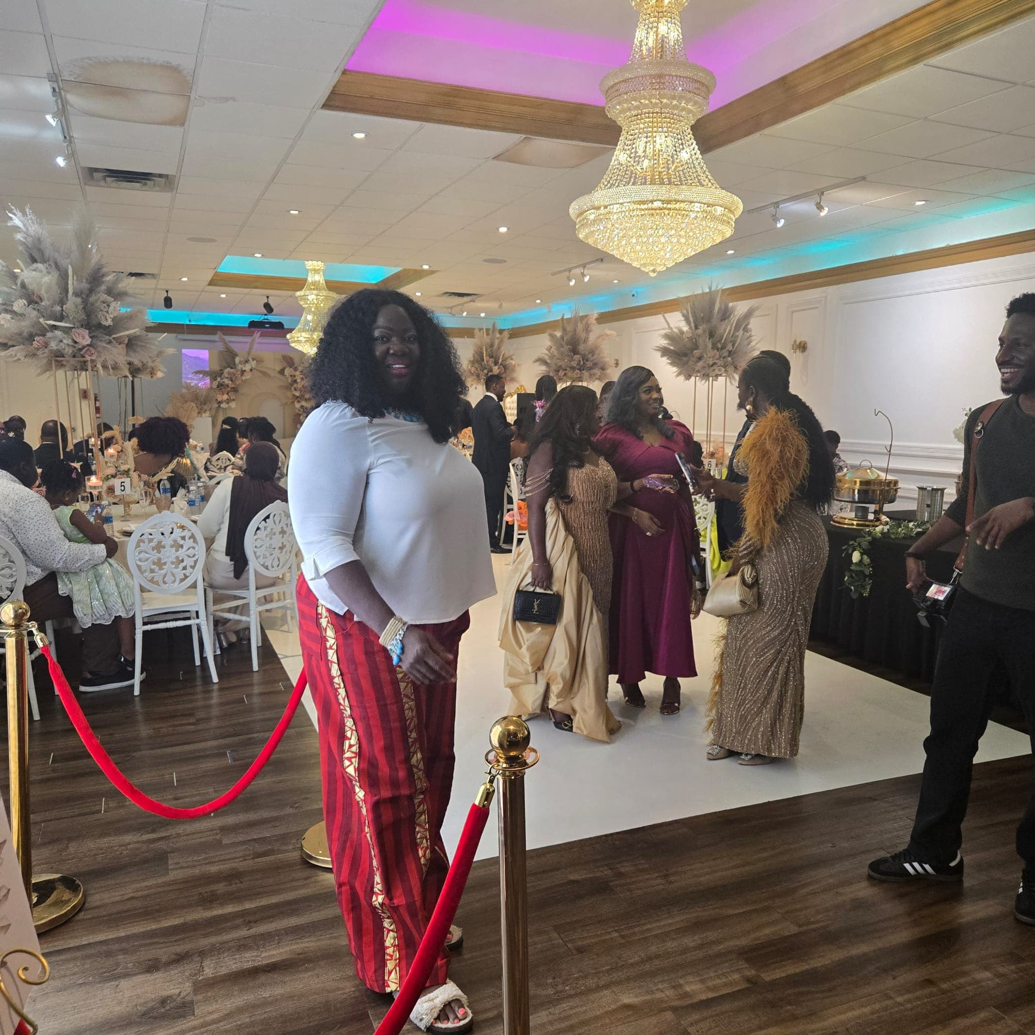Guests mingling on the white dance floor during a live event, red velvet ropes in the foreground.