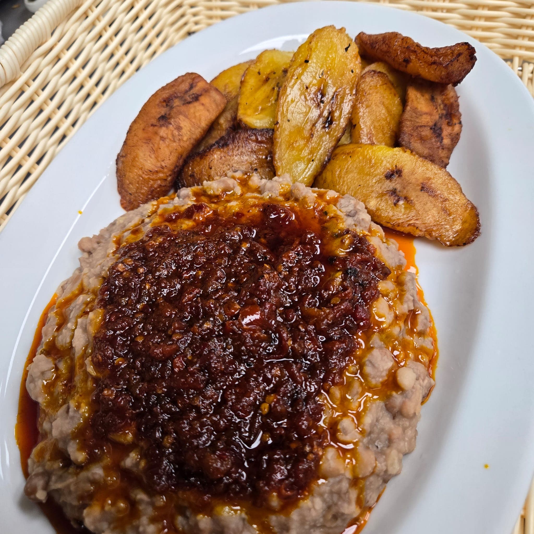 Ewa agoyin beans under rich pepper sauce with fried plantain.