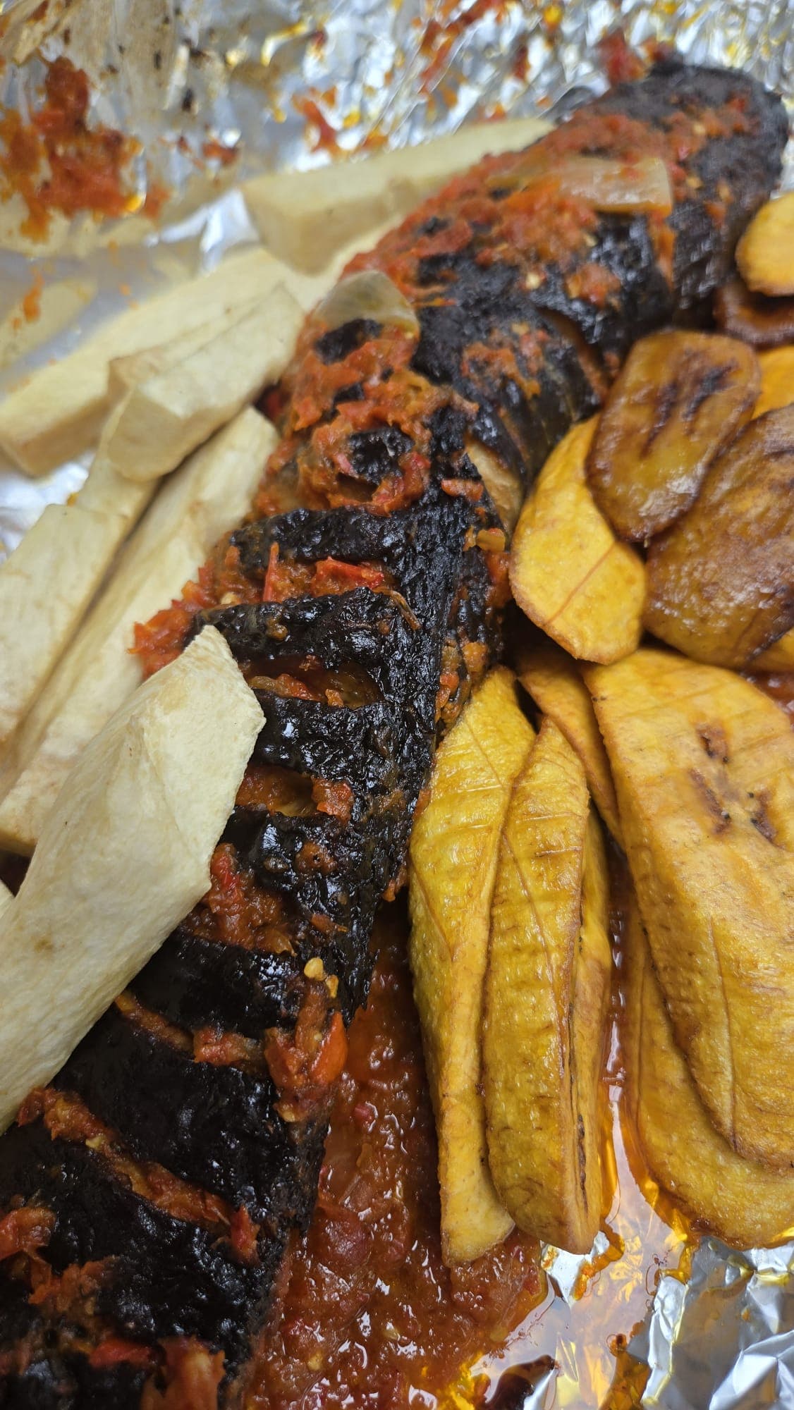 Grilled whole catfish in pepper sauce with fried plantain and yam.