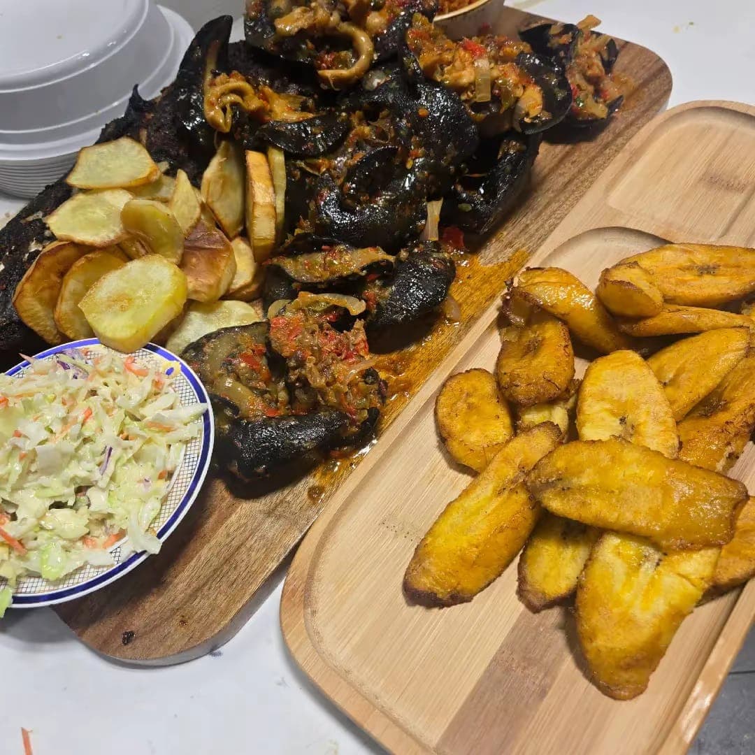 Peppered jumbo snails in green pepper sauce with fried plantain, potato and coleslaw.