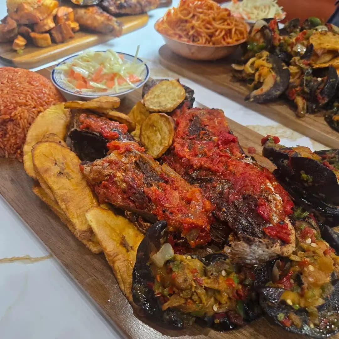 Whole grilled catfish in pepper sauce with fried plantain, potato and jollof rice.